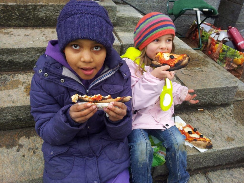 Zwei Kinder geniessen auf dem Matthäusmarkt eine Pizza aus dem Lehmbackofen. 